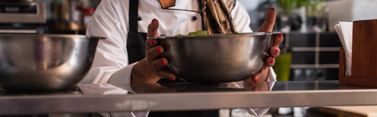 cropped view of tattooed african american woman holding bowl in professional kitchen, banner.