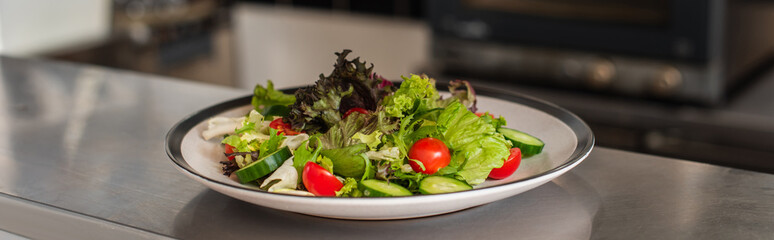 plate with freshly cooked salad in professional kitchen, banner.