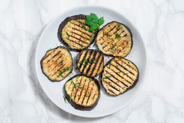 Healthy food grilled eggplants in plate on white marble background.