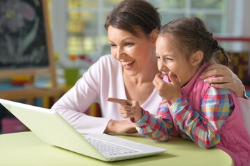 Teenage girl with mom with laptop in children's room