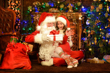 Santa Claus in a traditional costume with a girl in a room