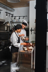 cheerful multiethnic chefs cooking together in professional kitchen.