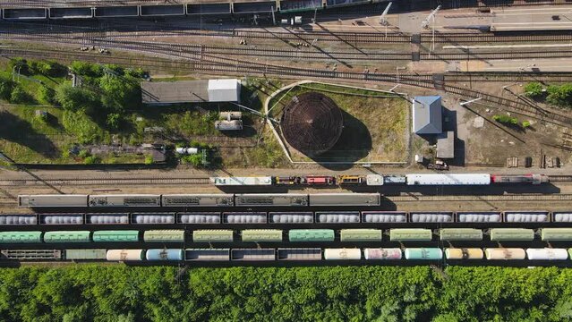 Railway with moving and standing in several rows of wagons, aerial view. Flight over long trains loaded with goods. The concept of logistics and cargo transportation. UHD 4K.