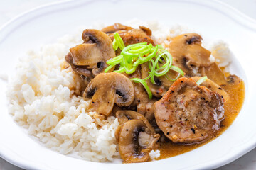 slices of pork meat with mushrooms and gravy served with rice
