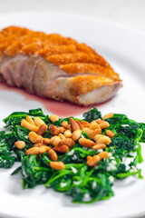 roasted duck breast served with salad of spinach leaves and pine nuts