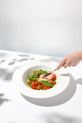 Summer salad with poached egg and vegetables. Female hand with knife. Hand sliced egg  on green salad. Action food menu. Trendy concept menu. Lifestyle food - vegetables salad with poached egg.