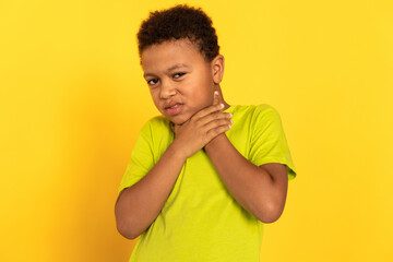 Portrait of unwell preteen boy suffering from sore throat. Mixed race child wearing green T-shirt touching his neck. Childs health problems concept