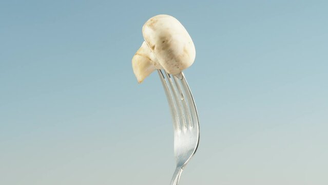 Champignon, impaled on a fork, rotates against the blue sky. close-up