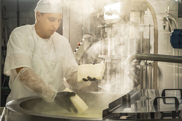 Man is a cheese maker in the process of producing different varieties of cheese in the industry. Milk cheese making