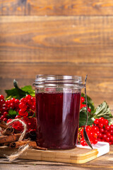 Autumn jam recipe, conservation and harvest season. Homemade red jam from organic viburnum berries, with fresh berries on twigs and cinnamon