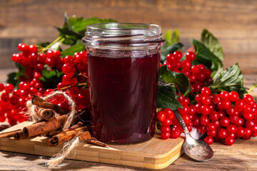 Autumn jam recipe, conservation and harvest season. Homemade red jam from organic viburnum berries, with fresh berries on twigs and cinnamon