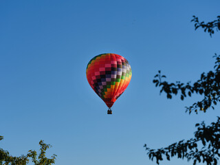 Fototapeta na wymiar Colorful hot air balloon flying through the blue sky