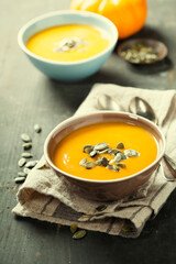 Pumpkin soup in a bowl on a wooden surface with copy space