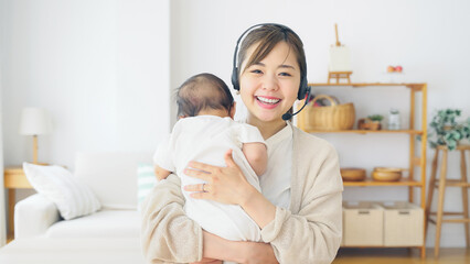 赤ちゃんを抱っこしながらビデオ通話で話す女性