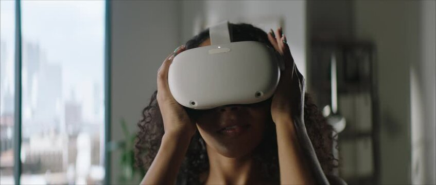 DOLLY IN Attractive African American female puts on a VR virtual reality metaverse headset at home