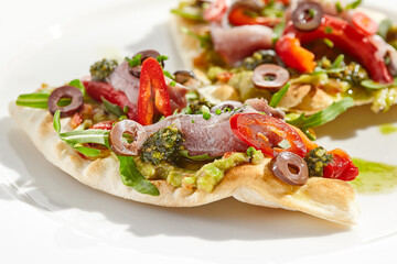 Tapas with avocado cream, anchovy, paprika and kalamata olives on focaccia. Bruschetta with guacamole and anchovy isolated on white background. Appetizer contemporary concept. Fish antipasti.