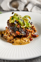 Braised beef cheeks with pearl barley and celery in creamy mushroom sauce. Veal cheek with mushroom risotto on gray stone background. Main course concept. Food menu for restaurant.