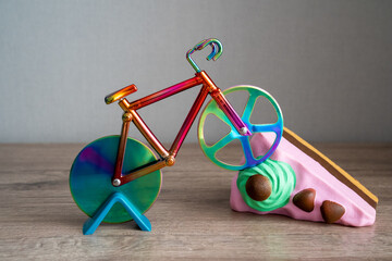 colorful knife cutter in shape bicycle on bright birthday piece of sponge cake, cut a cake,...
