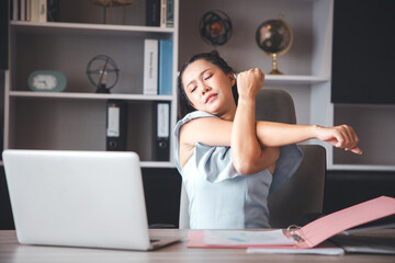 A businesswoman who works in the office looks tired and stressed by pressing her hands