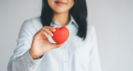 Woman hands holding a red heart, heart health insurance, health care.