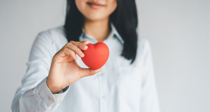Woman hands holding a red heart, heart health insurance, health care.