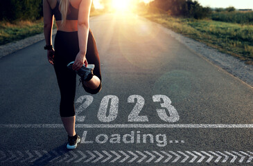 Naklejka na ściany i meble Sporty girl who is at the starting line to pass in 2023 year and the Loading bar drawn on asphalt. Concept of new professional achievements in the new year 2023 and success.