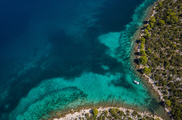 Naklejka na ściany i meble Aerial shot above beautiful turquoise water harbor with a white yacht near small island in Adriatic sea near from Sibenik city, Dalmatia in Croatia. Nature, environment concept.