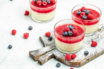 Raspberry Panna cotta with raspberry jelly on a light background. Berry dessert with cream sauce in small jars. place for text