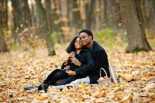 Loving black couple have a picnic in autumn park and drink a tea