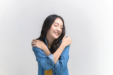 Self care and self esteem concept, Happy young beautiful Asian woman in colorful clothing hugging herself isolated on white background. People emotion portrait concept.	