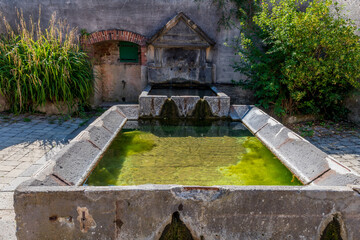 Fototapeta na wymiar Ancien lavoir datant de Napoléon 1er servant actuellement de fontaine avec son eau claire dans un petit village du puy de dôme