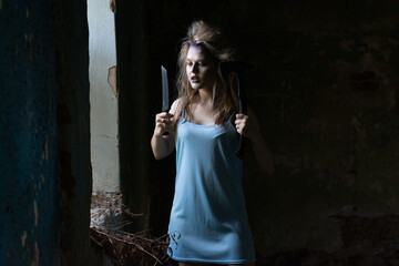 scary zombie girl with a knife and an axe in an abandoned house.an idea for Halloween and the day of the dead