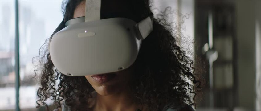 Portrait of excited African American female using her VR virtual reality metaverse headset at home