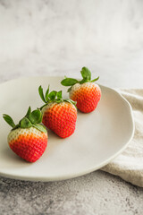 strawberry fresh and juicy fruit on white plate and light background minimalist photo. Space for text