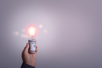 Light bulb on a rolled of money. Copy space for text. Concept of increasing the electricity costs...