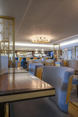 Elegant Art Deco interior design furnishing bar lounge area onboard ocean liner cruiseship cruise ship with chairs, tables, bar counter and brass room dividers