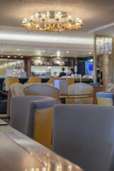 Elegant Art Deco interior design furnishing bar lounge area onboard ocean liner cruiseship cruise ship with chairs, tables, bar counter and brass room dividers