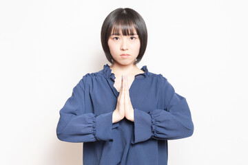 白バックの前で、謝っている若い女性