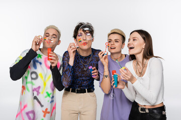 joyful lgbtq community friends having fun and blowing soap bubbles isolated on grey.