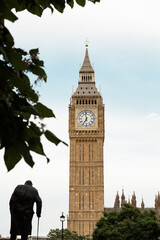 Big Ben in London UK England tower with tree and sculpture in the foreground