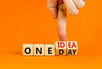 One day and idea symbol. Concept words One day and One idea on wooden cubes. Businessman hand. Beautiful orange table orange background. Business One day and idea concept. Copy space.