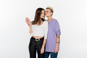 young and trendy lesbian women holding hands isolated on grey.