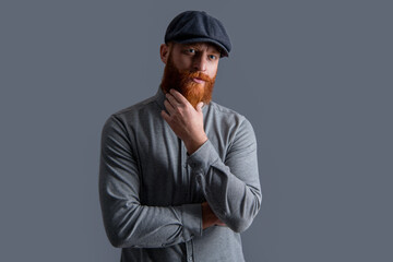 Irish guy isolated on grey. Serious guy stroking red beard. Bearded guy studio