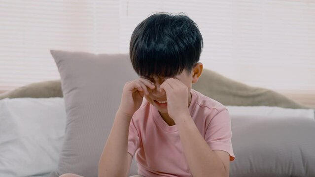 4K, Asian boy, wearing a pink T-shirt, Sit and cry and rub both eyes with both hands, He did so with regret, He did so with regret. , and he sat on the bed crying for a long time, frowning.