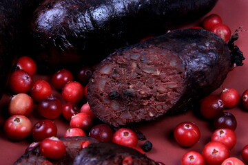 Baked blood sausage on a red plate decorated with red cranberries, Traditional Latvian blood...