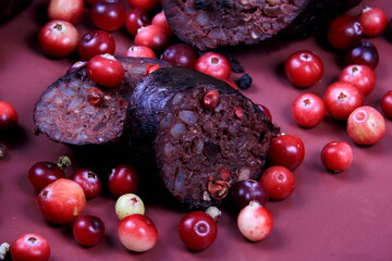 Baked blood sausage on a red plate decorated with red cranberries, Traditional Latvian blood...