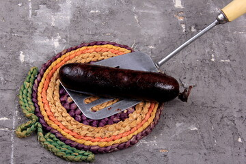 One blood sausage on a silver metal cooking spatula,Traditional latvian blood sausages
