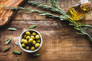 aceitunas variedad manzanilla en un bol, con una rama de olivo, una tabla de cortar y una aceitera...