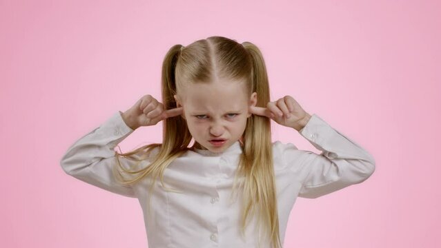 Portrait of grumpy little girl closing ears with fingers and shaking head, expressing negativity and obnoxiousness
