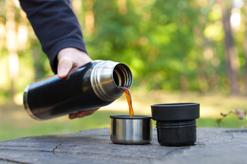 Man pouring coffee from thermos flask outdoors